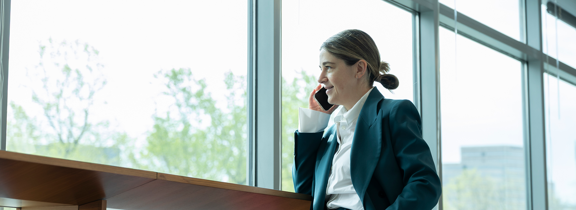 A Freddie Mac employee on her phone and looking outside a window.