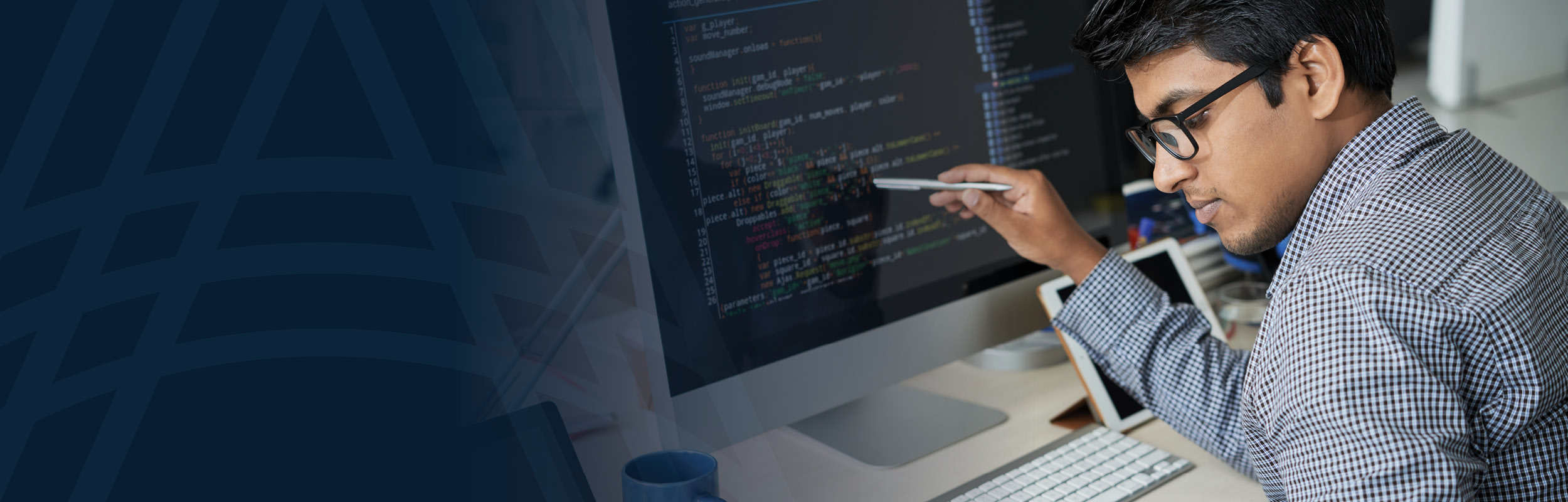male engineer wearing glasses gazing down while writing systems and software code